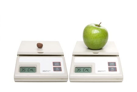A scale with chocolate candy and one with an apple.の写真素材