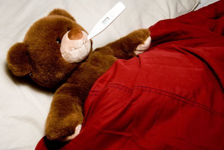 A sick teddy bear taking its temperature.