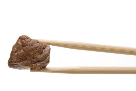 A piece of Japanese Steak being held by chopsticks.の写真素材
