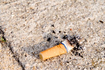 A discarded cigarette butt on a sidewalk.