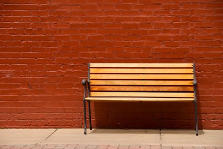 A bench beside a red brick wall.の写真素材