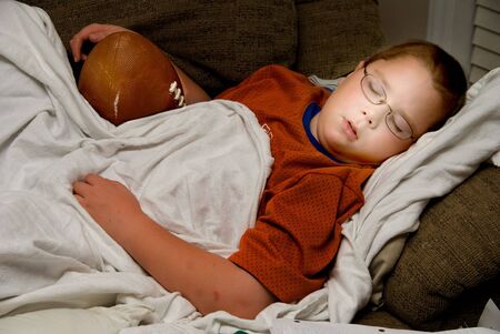 A young boy sleeping with his football.の写真素材