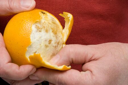 A person in the process of peeling an orangeの写真素材