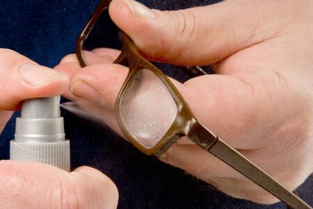 A person using Eyeglass Cleaner to clean a pair of reading glasses.の写真素材