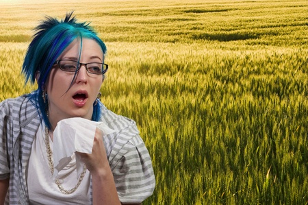 A beautiful woman with a cold, hay fever or allergies blowing her noseの写真素材