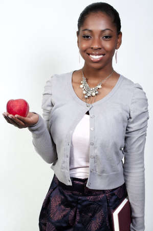 A young African American student teenager holding a book and an appleの写真素材