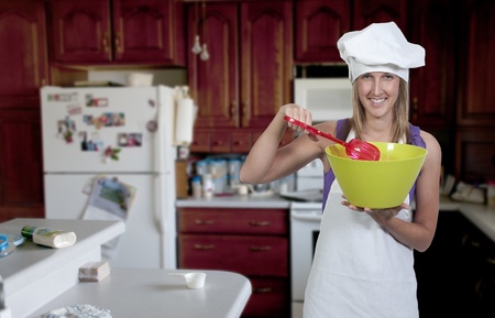 A beautiful woman chef holding a salad bowl and tongsの写真素材