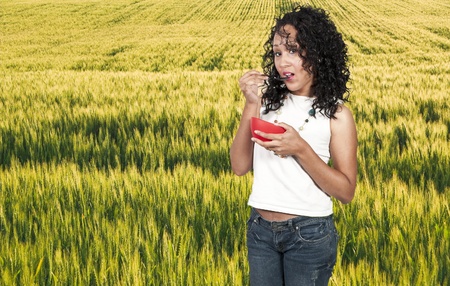 A beautiful woman eating food from a bowlの写真素材