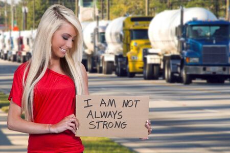 A beautiful young woman holding up a siagn that says I am not always strongの写真素材