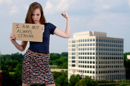 A beautiful young teenage woman holding up a siagn that says I am not always strongの写真素材