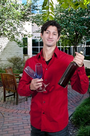 Handsome young man holding a wine glass and wine bottleの写真素材
