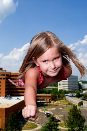 Beautiful little girl super hero flying through the skyの写真素材