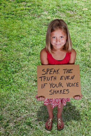 Beautiful little girl holding up an inspirational signの写真素材