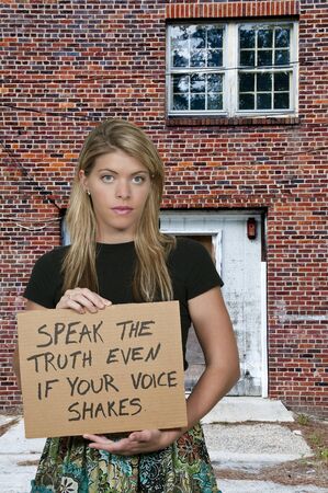 A beautiful young woman holding up an inspirational signの写真素材