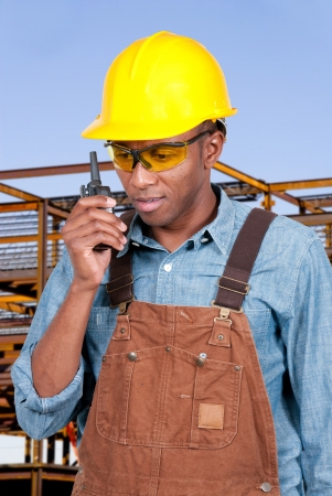 Handsome black man construction worker talking on a walkie talkieの写真素材