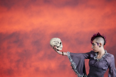 Beautiful young punk rock alternative lifestyle woman holding a skullの写真素材