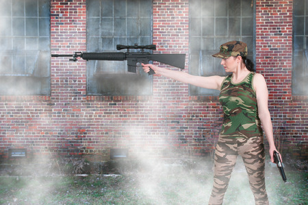 Beautiful young woman holding an automatic assault rifle and pistolの写真素材
