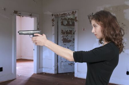 Beautiful woman with a loaded handgun pistolの写真素材