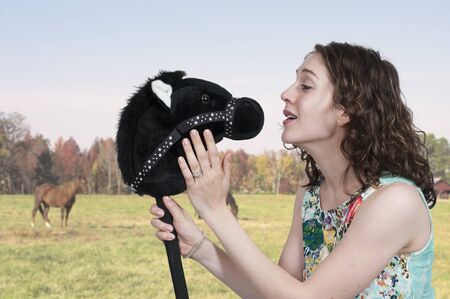 Woman talking to a toy stick horseの写真素材