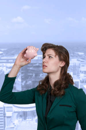 Bbeautiful woman holding a piggy bank full of money she has savedの写真素材