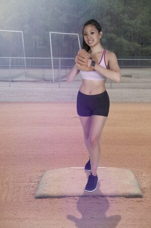 Beautiful woman baseball pitcher getting ready to throw a ball in a gameの写真素材