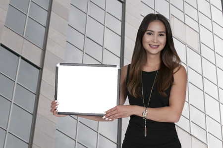 Beautiful young woman holding up a blank signの写真素材