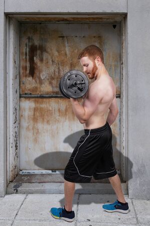 Handsome young muscular man lifting a weightの写真素材