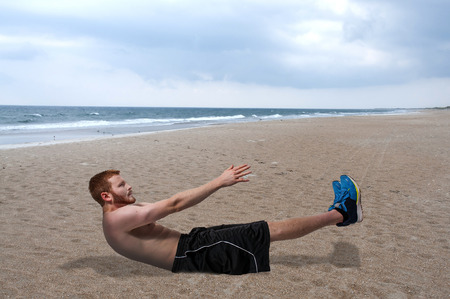 Young man doing exercises by doing crunchesの写真素材