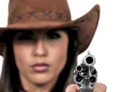 Old western relvolver barrel held by an out of focus woman in a cowboy hat