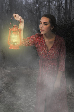Woman looking with an old fashoned lanternの写真素材