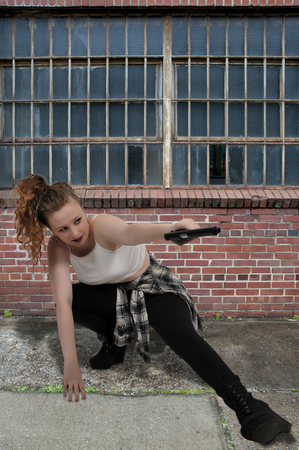 Beautiful young woman holding a loaded handgunの写真素材