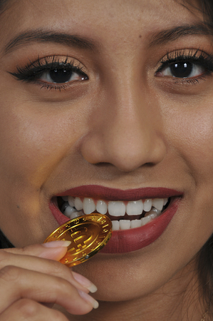 Woman biting the Electonic Currency known as Bitcoinの写真素材