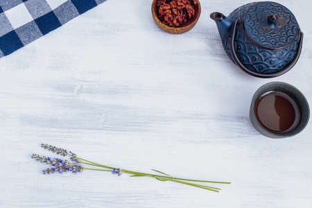 iron teapot and ceramic teacup with nuts and lavender bouquet on white background, copy space, top viewの写真素材