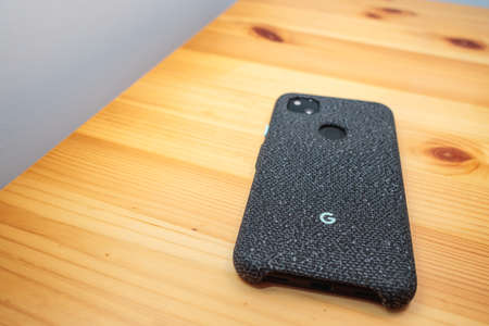 Google Pixel 4a whit case on desk, focus in Google logo. Copy Space