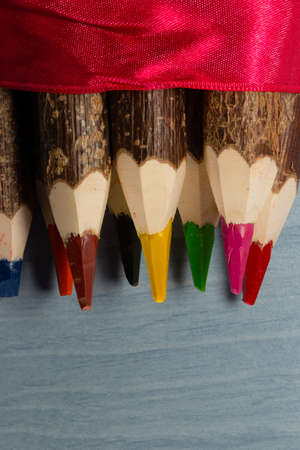 Colored pencils made of natural wood. They are made of unfinished wood on which you can still see the barkの写真素材