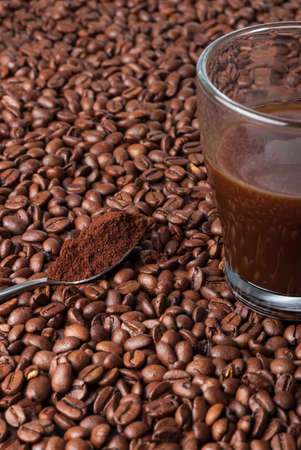 coffee beans background with coffee beans, a cup of coffee and a teaspoon of ground coffeeの写真素材