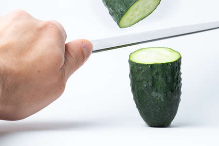 cucumber that is cut by a knife in two and the other half is in the airの写真素材