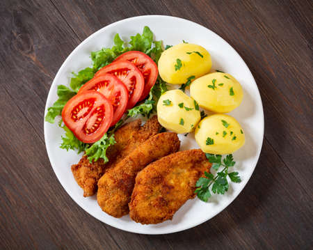 fried chicken fillets with potatoes and tomatoの写真素材