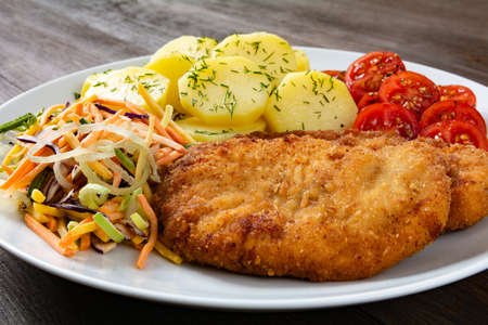 fried chicken fillets with potatoes, salad and tomatoの写真素材
