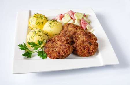 Fried cutlets with boiled potatoes and salad on white plate.の写真素材