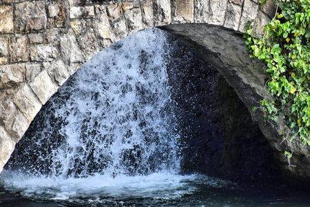Water falls down a cascade behind a little stone bridge at the rhine falls in Switzerland 20.5.2020の写真素材