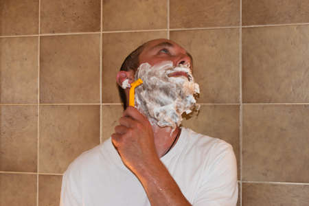 Vaduz, Liechtenstein July 1, 2021 A man with a big beard is standing in a bathroom with his shaverの写真素材