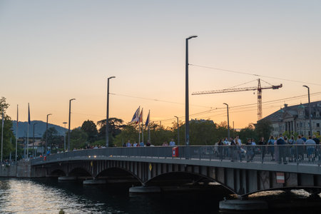 Zurich, Switzerland, September 4, 2021 Pedestrians are crossing the Quaibridge over the Limmat river in the eveningのeditorial素材