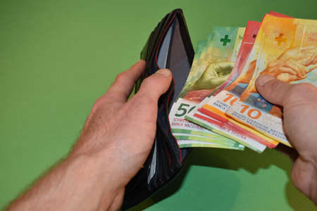 Vaduz, Liechtenstein, November 22, 2021 Taking off a few bills in the swiss currency from a wallet
