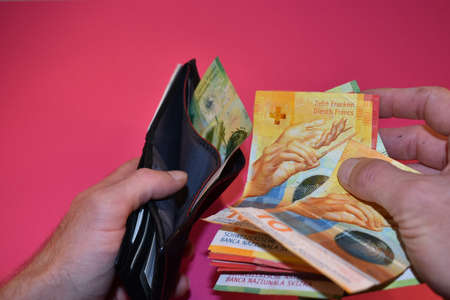 Vaduz, Liechtenstein, November 22, 2021 Taking off some cash in the swiss currency from a walletの写真素材