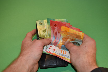 Vaduz, Liechtenstein, November 22, 2021 Taking off a few bills in the swiss currency from a wallet
