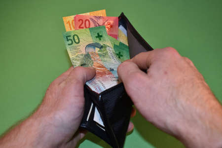 Vaduz, Liechtenstein, November 22, 2021 Taking off a few bills in the swiss currency from a wallet