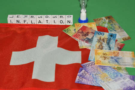 Vaduz, Liechtenstein, November 22, 2021 Switzerland national flag with some toy money and the word inflationの写真素材