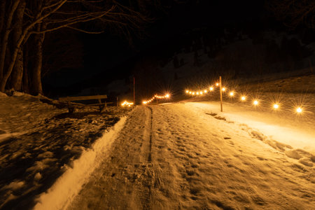 Saint Margrethenberg, Switzerland, December 19, 2021 Snow covered pedestrian way at night...