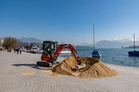 Lucerne, Switzerland, March 10, 2022 Excavator and a heap of sand at the water promenade